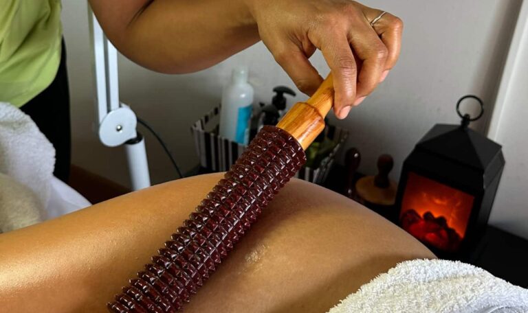 Mujer recibiendo maderoterapia corporal con instrumentos de madera en spa elegante — técnica reductora y relajante.