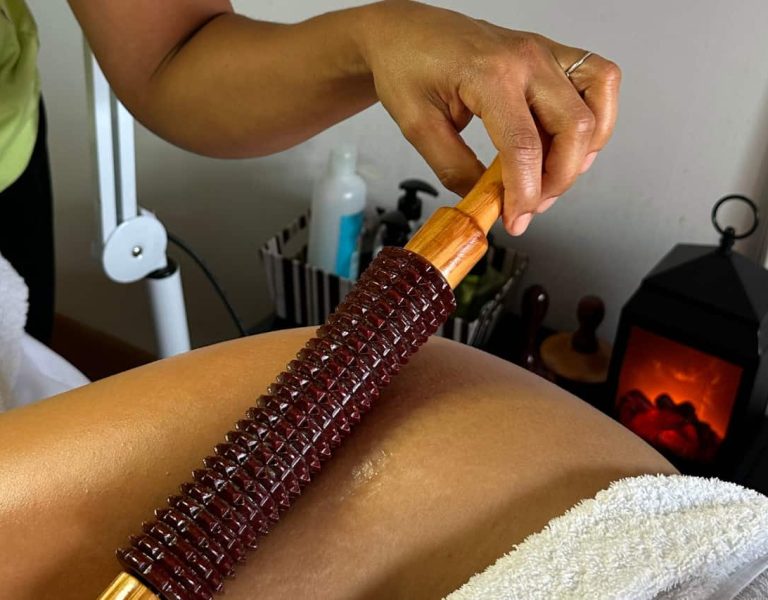 Mujer recibiendo maderoterapia corporal con instrumentos de madera en spa elegante — técnica reductora y relajante.